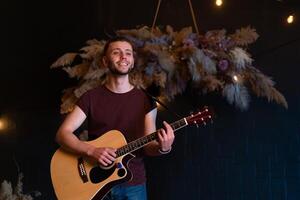 männlich Musiker spielen akustisch Gitarre. Gitarrist Theaterstücke klassisch Gitarre auf Bühne im Konzert foto