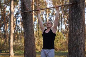 gut aussehend kaukasisch Männer Klimmzug draussen trainieren Kreuz Ausbildung Morgen Pumpen oben Arm ausüben Sport Boden Natur Wald foto