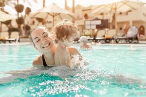 Mama und wenig Tochter sind gespielt im das öffnen Schwimmen Schwimmbad. Familie mit einer Kind auf Ferien im warm Länder. positiv Menschen auf Urlaub. foto