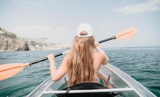 Frau im Kajak zurück Sicht. glücklich jung Frau mit lange Haar schwebend im transparent Kajak auf das Kristall klar Meer. Sommer- Urlaub Ferien und heiter weiblich Menschen entspannend haben Spaß auf das Boot foto