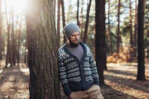 ein jung Mann mit ein Bart Spaziergänge im ein Kiefer Wald. Porträt von ein brutal bärtig Mann Herbst Wald foto