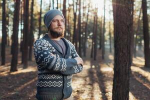 ein jung Mann mit ein Bart Spaziergänge im ein Kiefer Wald. Porträt von ein brutal bärtig Mann Herbst Wald foto