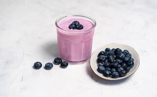 lecker frisch Blaubeere Joghurt Shake Dessert im Glas Stehen auf Weiß Tabelle Hintergrund. foto