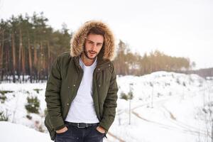 attraktiv bärtig Mann Stehen draußen im Winter Jahreszeit Wald. foto