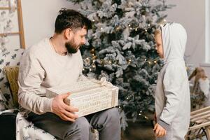 Urlaub Weihnachten gut aussehend Vater spielen mit klein süß Sohn in der Nähe von dekoriert Neu Jahr Baum beim Zuhause foto