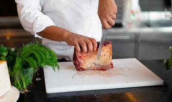 unkenntlich jung afrikanisch Koch Stehen im Fachmann Küche im Restaurant vorbereiten ein Mahlzeit von Fleisch und Käse Gemüse. foto