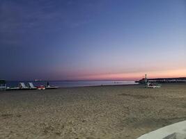 Abend leeren groß Strand auf das Strand. Rosa Sonnenuntergang. foto