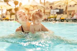 Mama und wenig Tochter sind gespielt im das öffnen Schwimmen Schwimmbad. Familie mit einer Kind auf Ferien im warm Länder. positiv Menschen auf Urlaub. foto