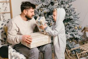 Urlaub Weihnachten gut aussehend Vater spielen mit klein süß Sohn in der Nähe von dekoriert Neu Jahr Baum beim Zuhause foto