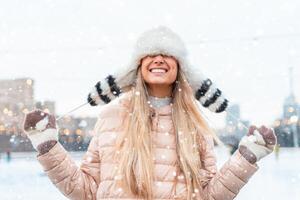 glücklich Winter Zeit im groß Stadt charmant Mädchen Stehen Straße gekleidet komisch flauschige Hut. genießen Schneefall, ausdrücken Positivität, lächelnd zu Kamera foto