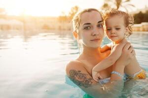 Mutter halten Kind beim tropisch Sommer- Schwimmen Schwimmbad Hintergrund foto