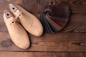 Leder Proben zum Schuhe und hölzern Schuh zuletzt auf dunkel hölzern Tisch. foto