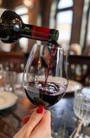 ai generiert Frau Gießen rot Wein in Glas im Restaurant foto