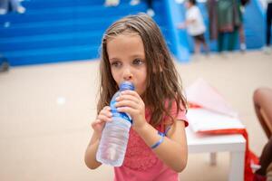 Kind trinken Wasser von Plastik Flasche draussen foto