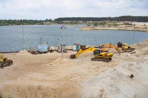 Sand Steinbruch Bergbau Industrie Ausrüstung Bagger Traktor Stehen Sand Land in der Nähe von See Wasser foto