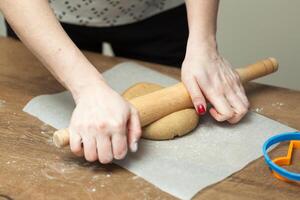 schließen oben von weiblich Hände Herstellung Kekse von frisch Teig beim Zuhause foto