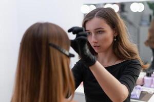jung Kosmetikerin kaukasisch Mädchen hält Modell- Augenbraue Korrektur foto
