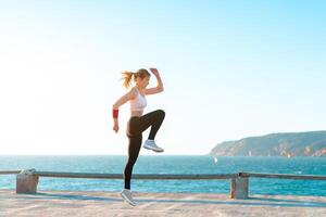 jung passen Frau Springen hoch auf Strand mit Sonnenuntergang, aktiv kaukasisch jung Erwachsene weiblich trainieren mit , Körpergewicht Ausbildung Übung zum Frau, selbst Motivation foto