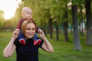 schön jung Mutter Spaziergänge mit ihr wenig Sohn im ein Sommer- Park foto