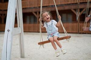 spielerisch Kind schwingen schwingen. froh wenig Mädchen abspielen haben Spaß Spielplatz Sommer foto