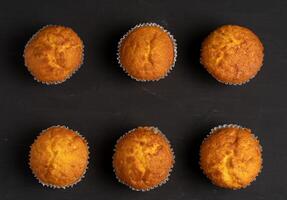 appetitlich Muffins Stand auf ein Tabelle oben Sicht. traditionell Gebäck auf ein dunkel Hintergrund Minimalismus. foto