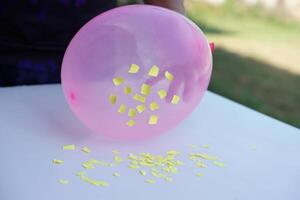 Nahansicht Hand halt Rosa Ballon zu tun Wissenschaft Experiment Über statisch Elektrizität von Ballon und Stücke von Papier. Konzept, Wissenschaft Lektion, Spaß und einfach Experiment. Bildung. Lehren AIDS. foto