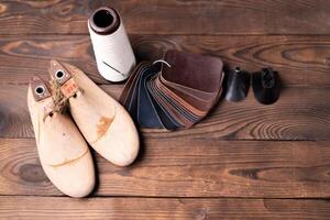 Leder Proben zum Schuhe und hölzern Schuh zuletzt auf dunkel hölzern Tisch. foto