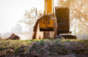 Baggerlader Arbeiten durch graben Boden beim Konstruktion Seite? ˅. Crawler Bagger graben auf Abriss Seite? ˅. Ausgraben Maschine. Erde ziehen um Maschine. Ausgrabung Fahrzeug. Konstruktion Geschäft. foto