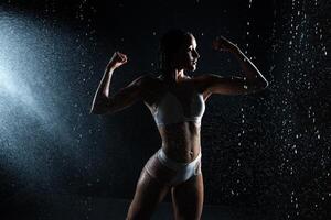 schön sportlich kaukasisch Mädchen mit ein perfekt Zahl ist Stehen unter das Wasser. Fitness Frau im ein sprühen von Wasser. Sport Frische foto