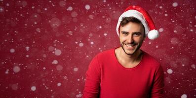 jung gut aussehend kaukasisch Kerl im rot Sweatshirt und Santa Hüte steht auf rot Hintergrund im Studio und und Zähne lächelnd foto