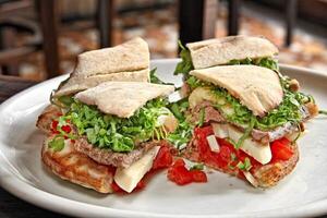 Steak Sandwich mit Kopfsalat, Tomaten und Käse auf Teller foto