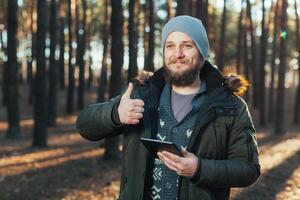 schließen oben Porträt von Erwachsene männlich Wanderer mit Digital Tab und suchen zum Ort während Wanderung im Natur. Mann auf Wanderung mit Digital Tablette zum Navigation. foto