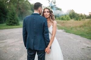 Braut und Bräutigam beim Hochzeit Tag Gehen draußen auf Sommer- Natur. Braut- Paar, glücklich frisch verheiratet Frau und Mann Umarmen im Grün Park. liebend Hochzeit Paar draussen. Braut und Bräutigam foto