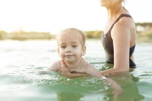 Mutter und Baby auf das Wasser. Mama und wenig Kind Schwimmen und spielen im Wasser. Familie Sommer- Ferien auf exotisch Insel. Reise mit Kinder. Sonne Schutz und schwimmen tragen. foto