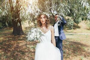 Braut und Bräutigam beim Hochzeit Tag Gehen draußen auf Sommer- Natur. Braut- Paar, glücklich frisch verheiratet Frau und Mann Umarmen im Grün Park. liebend Hochzeit Paar draussen. Braut und Bräutigam foto