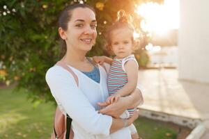 Mutter umarmen mit ihr wenig Tochter draussen im Natur auf sonnig Tag positiv Mensch Emotionen, Gefühle, Emotionen. foto