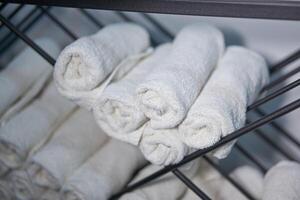 Weiß sauber Handtücher gerollt oben auf ein rollen sind gelagert auf Regale im ein Schönheit Salon im ein Friseur Spa. foto