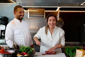 gut aussehend jung afrikanisch Koch ist Kochen zusammen mit seine kaukasisch Freundin im das Küche mit rot Wein wie ein Zutat. foto