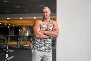 muskulös sportlich Bodybuilder Fitness Modell- Stehen Fitnessstudio foto