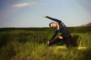 schön jung Brünette Frau tun Yoga im ein Feld von Weizen unter Sonnenstrahlen foto