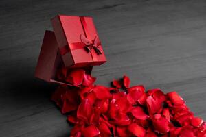 schön rot Rosen Nächster zu ein Geschenk rot Box auf ein dunkel Zement Hintergrund. foto
