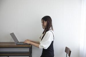 ein japanisch Frau Überprüfung Smartphone durch Fernbedienung Arbeit im das Zuhause Büro foto