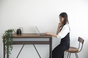 ein japanisch Frau Überprüfung Smartphone durch Fernbedienung Arbeit im das Zuhause Büro foto