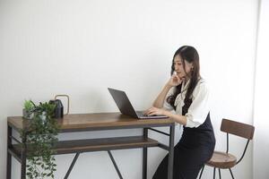 ein japanisch Frau Überprüfung Smartphone durch Fernbedienung Arbeit im das Zuhause Büro foto