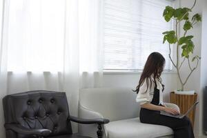 ein japanisch Frau Überprüfung Smartphone durch Fernbedienung Arbeit im das Zuhause Büro foto