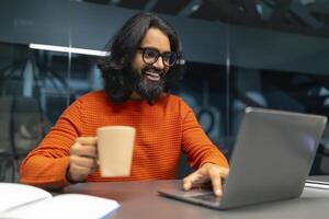 Mann nippen Kaffee während Arbeiten auf Laptop foto