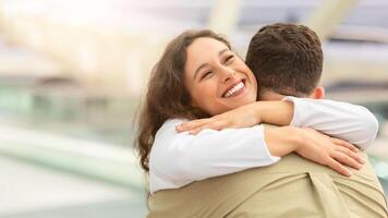 glücklich Wiedervereinigung. froh jung Frau umarmen ihr Mann beim Flughafen nach Ankunft foto
