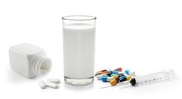 Pille und Glas Milch auf weißem Hintergrund