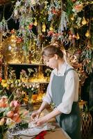 ein Frau im ihr Florist Geschäft sammelt Blumensträuße von Blumen. das Konzept von ein klein Geschäft. Blumensträuße von Tulpen zum das Urlaub auf März 8. foto