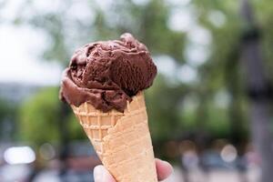 Hand halten köstlich Eis Sahne Waffel Kegel mit Schokolade foto